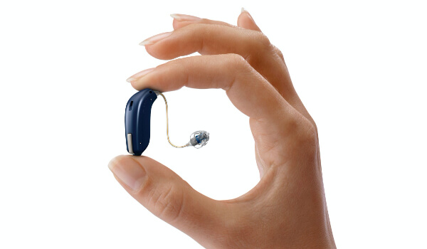 hand with hearing aid in between two fingers.